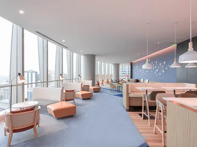 Modern hotel bar with concrete walls, lighting fixtures, and seating areas.