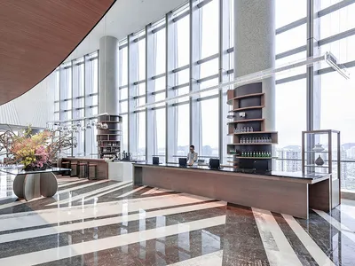 A modern hotel lobby featuring glass, wood, and marble materials.