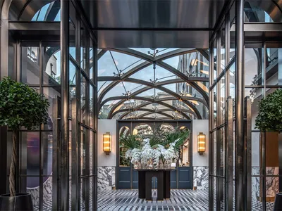 Modern hotel lobby featuring glass walls, marble flooring, and concrete columns.