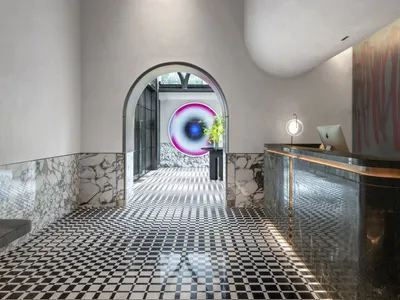 Modern hotel lobby with colorful glass sculpture, marble accents, and black and white checkered floor.
