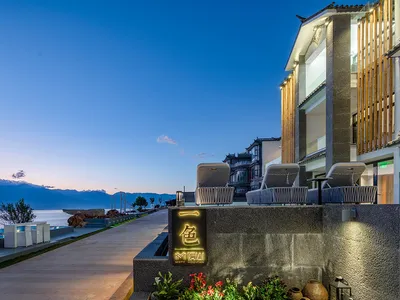 An evening view of a modern resort featuring a building with a prominent contemporary design, illuminated exterior lights, an