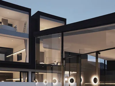 A modern restaurant exterior with glass walls at dusk, illuminated by warm interior lighting.