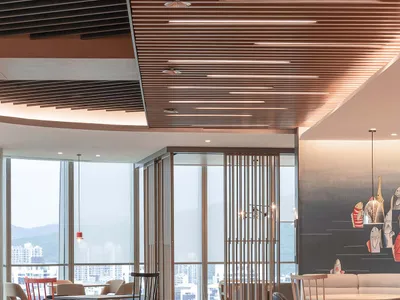 A modern, minimalist restaurant interior with wooden tables and chairs, large windows offering a view of the city, and a warm