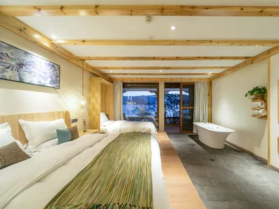 Modern industrial-style hotel room with wood and stone accents, featuring a minimalistic decor and a bathtub area with a scen