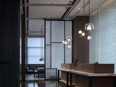 Modern hotel lobby featuring glass partitions, marble countertops, and wooden furniture.