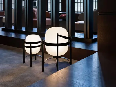 A modern hotel lobby with glass columns and light fixtures, featuring decorative vases on a wooden floor.