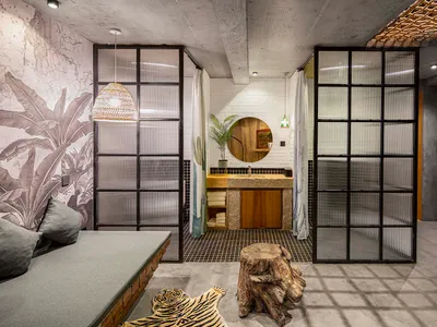 A modern industrial hotel suite featuring a concrete floor with a grid pattern, natural wood accents, and furniture designed