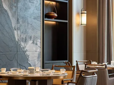 Modern restaurant interior with marble and wooden furniture, featuring a table set with cups and plates, and a hanging lanter