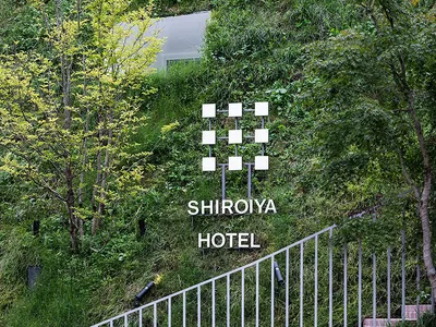A metal sign with the words 'SHIROIYA HOTEL' embedded in green foliage.