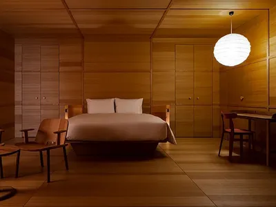Minimalist bedroom with wooden furniture, a large bed, and a hanging light fixture.