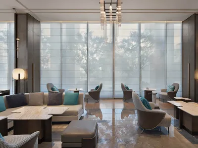 A modern hotel lobby with glass walls and metal furniture.