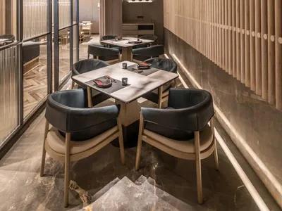 A modern restaurant interior featuring wooden chairs and tables with a distinctive chandelier.