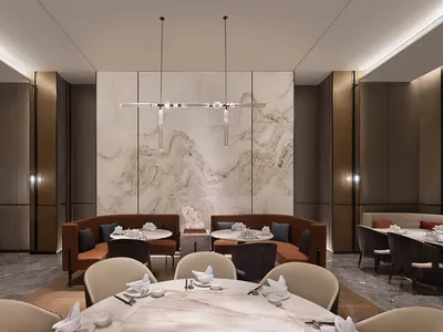 A modern restaurant interior featuring a large marble wall, round dining tables, and comfortable seating areas.