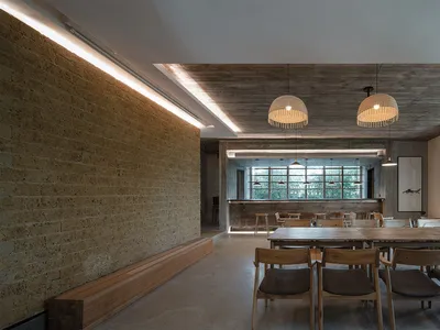 Industrial-themed restaurant interior with concrete walls, wooden furniture, and pendant lights.