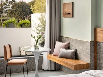 Minimalist bedroom featuring a concrete wall and wooden seating area.