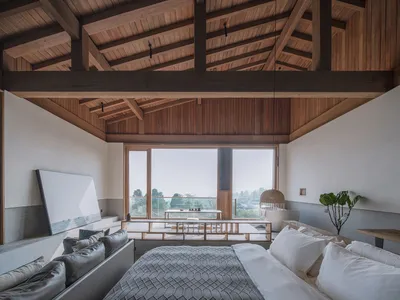 A minimalist bedroom featuring wooden furniture and a large window overlooking nature.