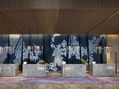 A modern hotel lobby reception area featuring marble countertops, patterned tiles, and illuminated lighting fixtures.