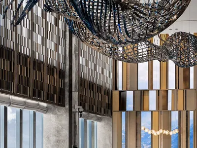 A modern hotel reception area with metallic sculptures and a receptionist desk.