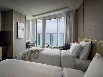 Modern hotel room with twin beds, television, and ocean view.