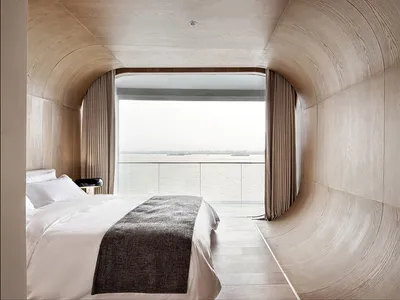 Modern minimalist bedroom featuring wood interiors and a view of the ocean.