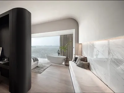 A modern minimalist bedroom featuring marble and wood materials.