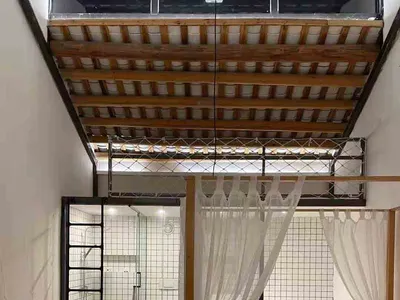 現代臥室室內，木質地板、配有薄紗簾的床，以及背景中白色瓷磚浴室。