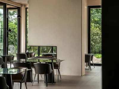 Modern interior of a restaurant featuring glass tables, metal chairs, and wooden flooring.