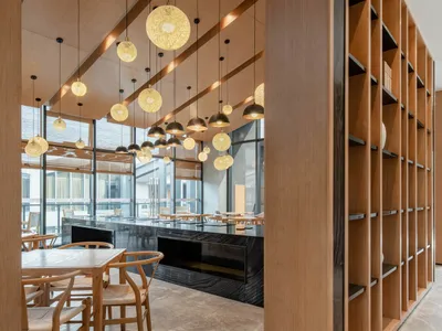 A modern restaurant facility with wooden furnishings, illuminated by spherical light fixtures.