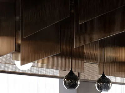 A modern restaurant interior featuring metallic textured panels and hanging light fixtures.