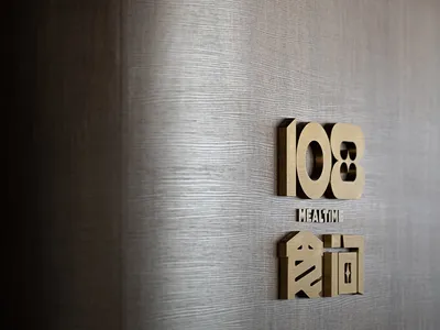 Modern, metallic brass signage with the number 108 and the text 'Mealtim' in a restaurant setting.