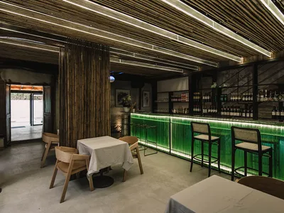 Modernly styled restaurant bar with concrete and green glass materials.