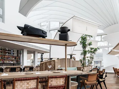 Modern restaurant interior with exposed wood ceiling beams and wooden flooring.