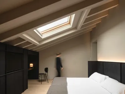 Minimalist bedroom with wooden furniture and a skylight.