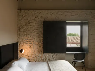 A modern minimalist bedroom with a bed, lamp, chair, and minimalist style