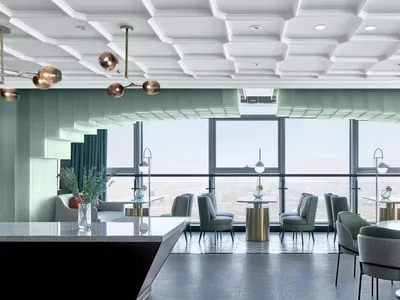 Modern restaurant interior with glass walls, metallic accents, and fabric seating.