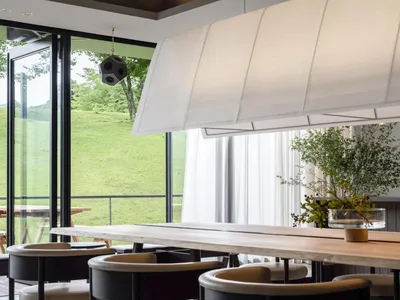 Modern, spacious restaurant interior with large windows showcasing a serene outdoor view, featuring minimalist design, white