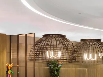 A modern restaurant interior with metal pendant lights, wooden tables, and glass panels.