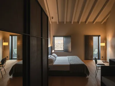 簡約臥室內擺放木質家具，可眺望瓦片屋頂景色。