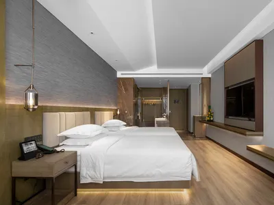 現代臥室，配有白色床品、大理石床頭板與皮革座椅。