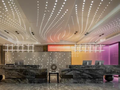 A modern hotel reception desk made of marble, featuring intricate lighting and a sleek design.