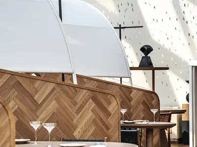 Modern restaurant interior with wooden tables, leather chairs, and contemporary design features.