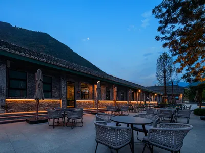 Outdoor seating area of a restaurant with brick exterior and mountain background.