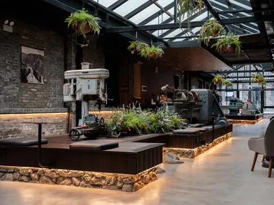 Industrial-themed restaurant bar featuring concrete flooring, metal accents, and glass plants.