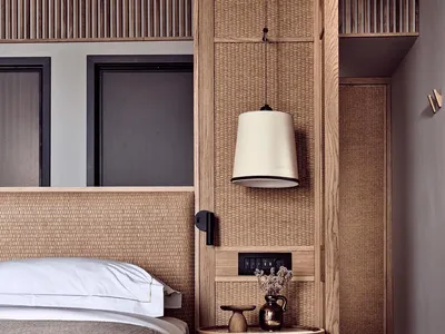 A minimalist bedroom with wooden furniture and decor, featuring a bed with a textured gray comforter and a woven headboard, a