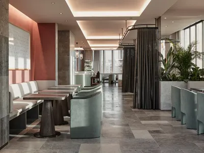 Modern restaurant interior with concrete flooring, white seating, and green plants.