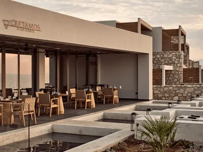 Modern restaurant exterior with glass walls, concrete ground, and wooden furniture.