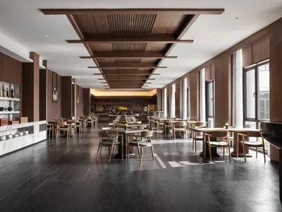 Industrial-style restaurant interior with marble countertops, wooden tables, and metallic bar.