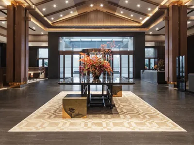 A spacious hotel lobby with a large wooden vase centerpiece and a high, vaulted wooden ceiling.