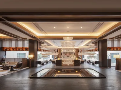 A modern hotel lobby with marble flooring, wooden beams, and a central water feature.