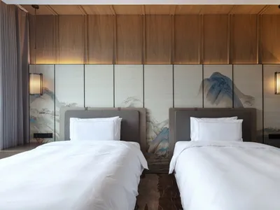 A modern hotel room featuring wooden paneling and twin beds.